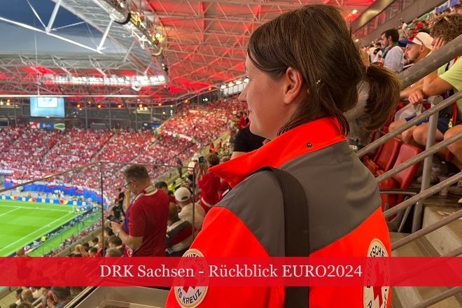 Einsatzkraft des DRK steht auf einer Tribüne im Stadion